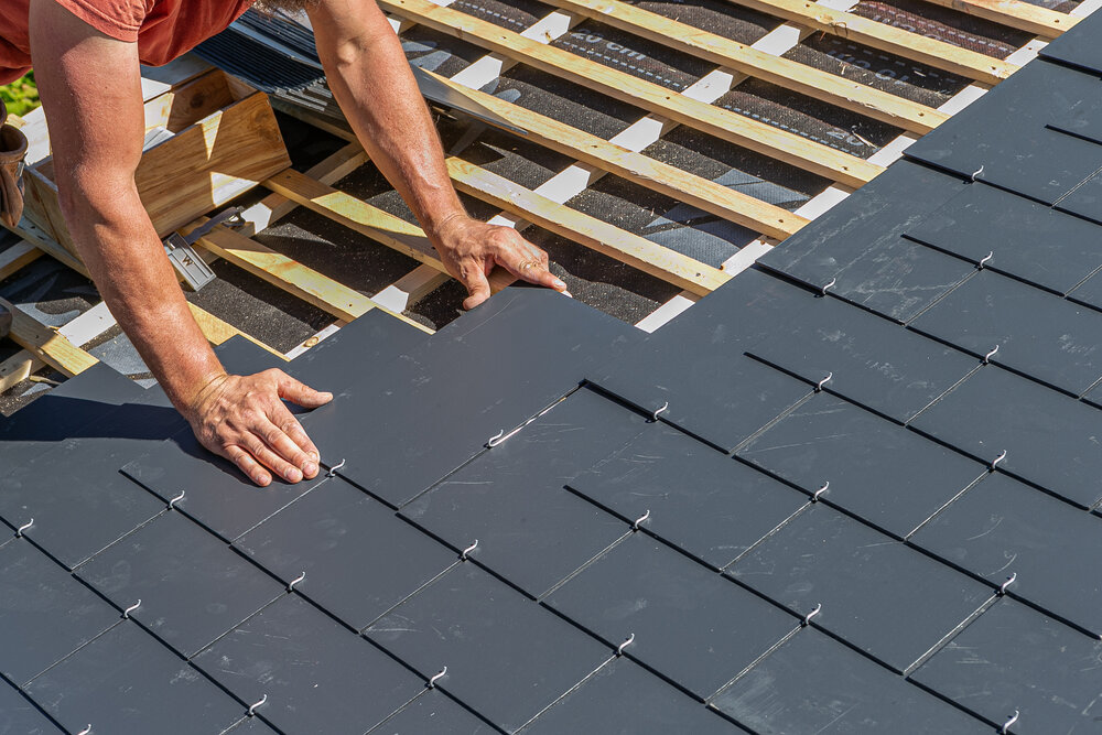 Roofing contractor installing slate roofing on a residential roof