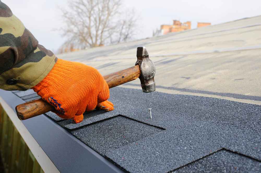Roofer installing an asphalt shingle roofing system
